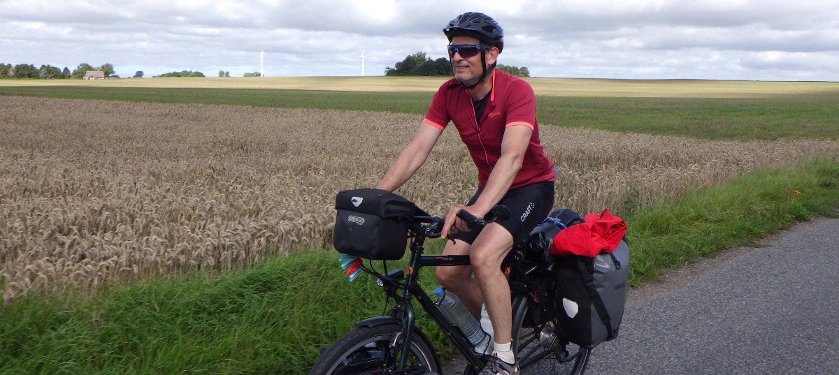 Jan-Willem op de fiets met landerijen op de achtergrond