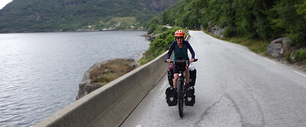 Saskia tegemoetkomend op de fiets op weg langs fjord
