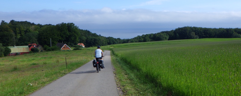 JW fietst door landerijen met de zee in de verte